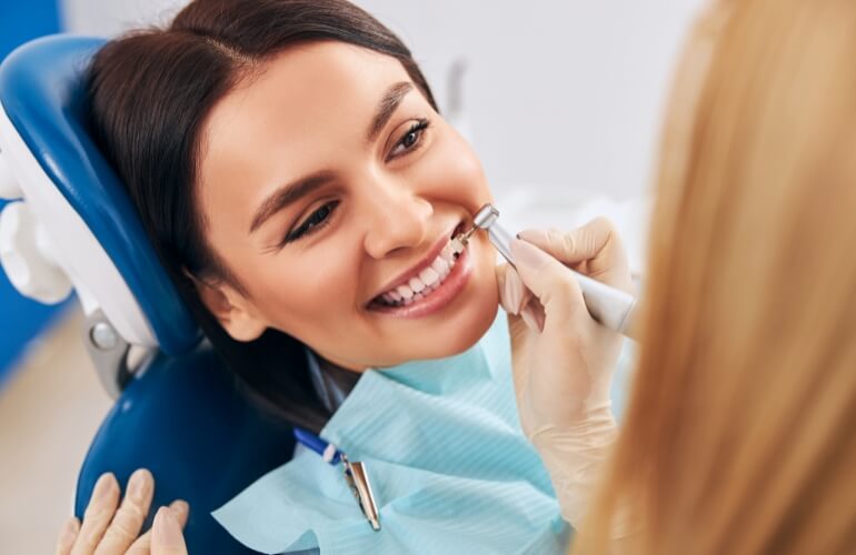 A woman smiles while seated in a dental chair