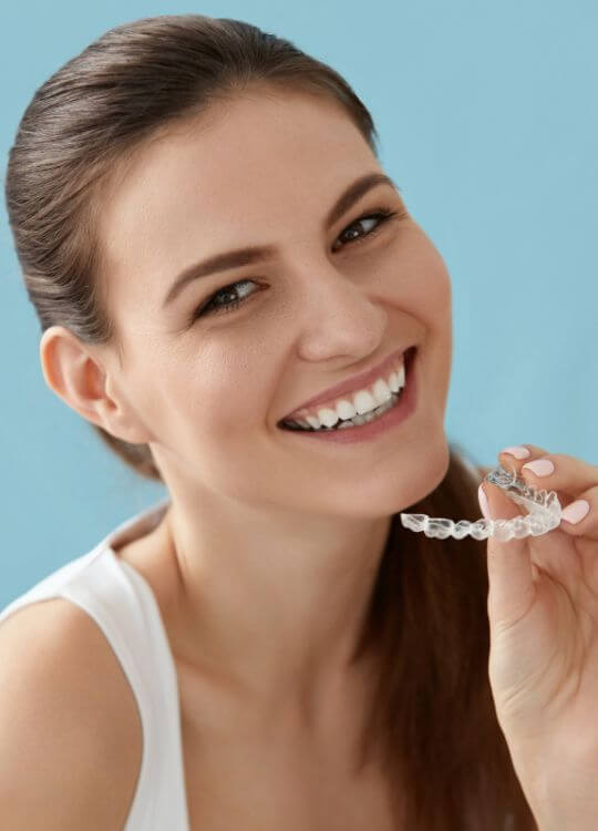 A woman is smiling and pointing to her teeth with her finger, showcasing her dental health and confidence