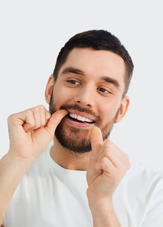 A man smiles brightly while brushing his teeth, showcasing the benefits of restorative dentistry for oral health.