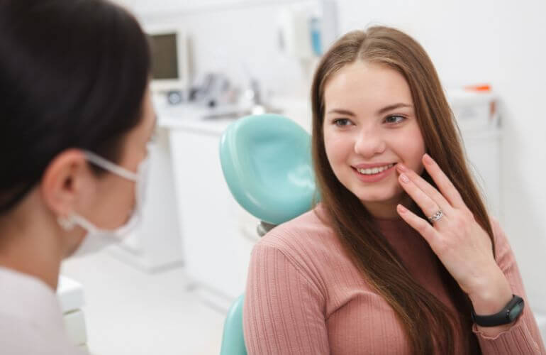 A woman smiles confidently while seated in a dental chair