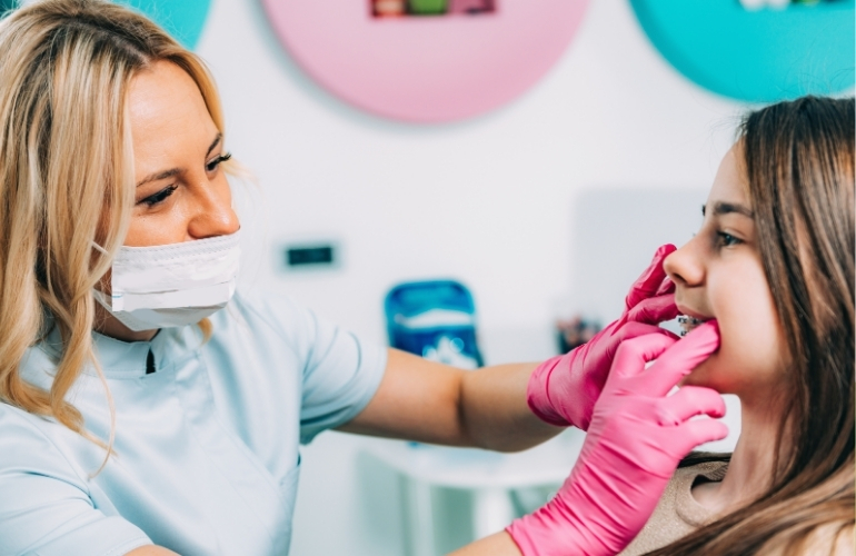 A woman receiving a dental cleaning from a dentist in a clinical setting