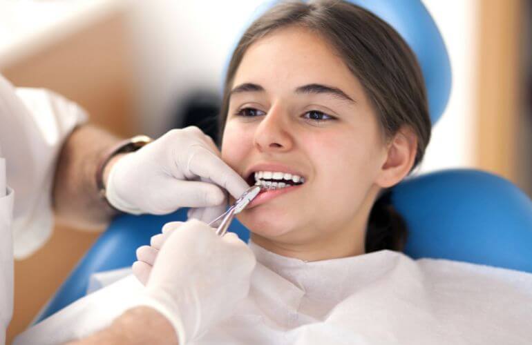 Dentist adjusting patient’s dental braces