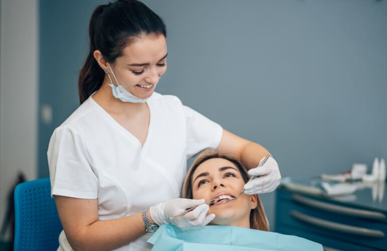 A dentist checks a woman's teeth in a clinical setting