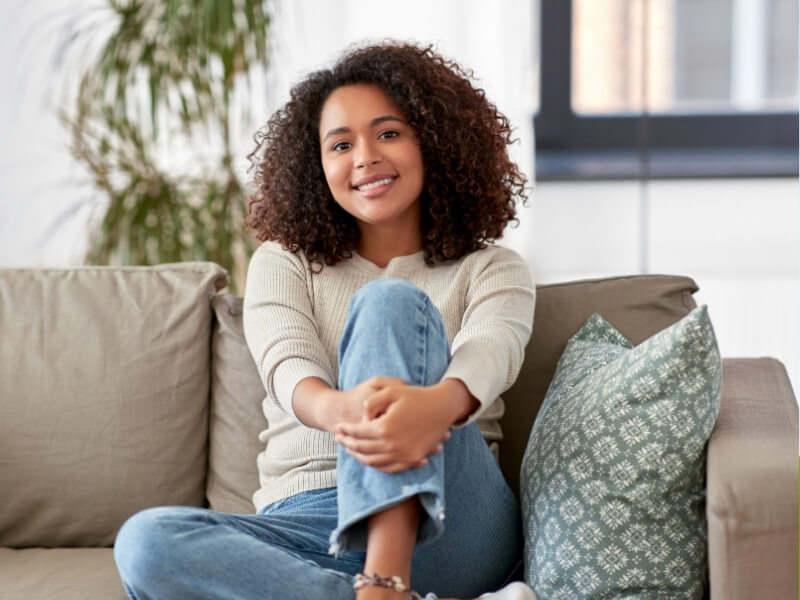 A woman with a bright smile sits comfortably