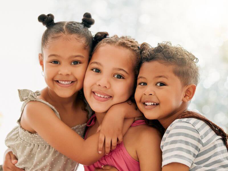 Three smiling kids hugging together