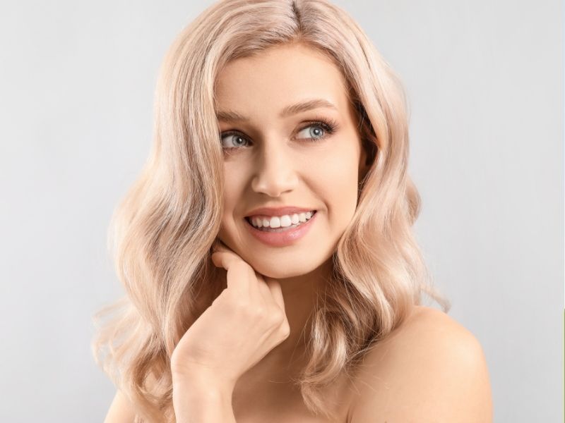  A woman with blonde hair smiles and poses confidently for the camera