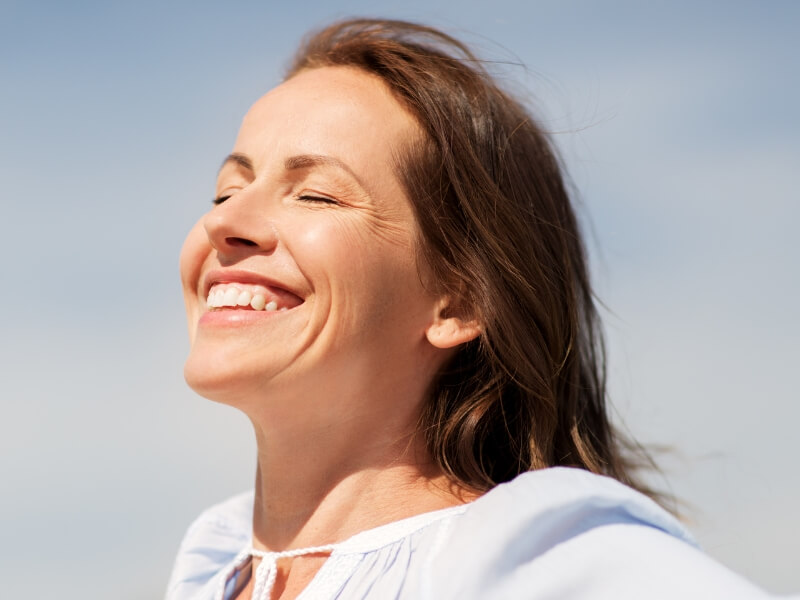 Woman smiling outdoors with eyes closed